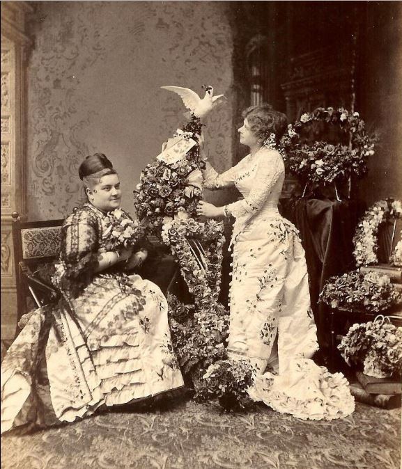 Flower Ladies display their hand-crafted floral arrangements, including a harp, and horseshoe, at a funeral to show their support.